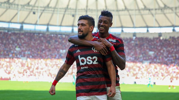 Arrscaeta, abraçado por Bruno Henrique, foi o destaque na vitória sobre o Goiás. Foto: Buda Mendes/Getty Images/Via UOL