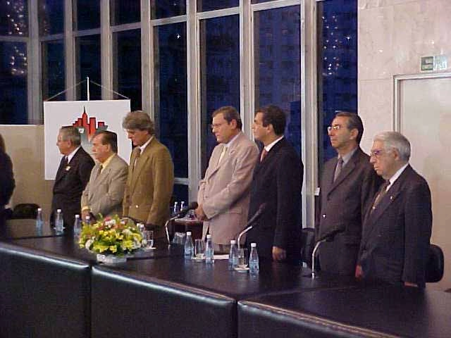 Momento da execução do Hino Nacional Brasileiro durante a cerimônia em que Milton Neves recebeu o Título de Cidadão Paulistano, em 10 de fevereiro de 2003. Da esquerda para a direita, os dois primeiros são Joseval Peixoto e Dalmo Pessoa. O quarto é Milton Neves, seguido por Celso Jatene, Silvio Torres e Murillo Antunes Alves