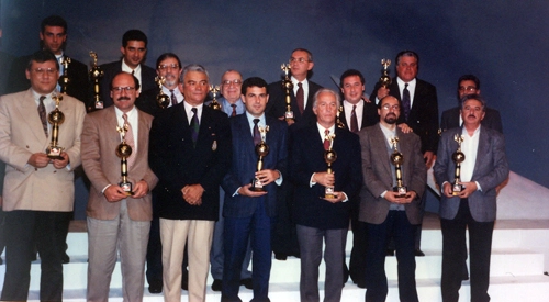 Milton Neves exibindo mais um troféu que ganhou em sua carreira ao lado de grandes companheiros de imprensa e homens do futebol. A foto é de meados da década de 1980 e foi tirada no teatro Gazeta. Na fila de cima temos, da esquerda para a direita, Luciano Junior, Tata Muniz, Kalef João Francisco e personagem não identificado; na fila do meio estão Sérgio Carvalho, Constantino Cury, Fernando Casal de Rey e o professor José Teixeira; na primeira fila vemos Milton Neves, Brunoro, Olten Ayres de Abreu, José Roberto Guimarâes, Valdir Joaquim de Moraes, Wanderley Nogueira e Fiori Giglioti.