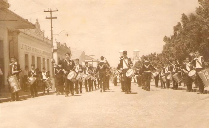 Desfile da querida fanfarra do CEPSAM (Colégio Estadual Professor Salatiel de Almeida), com dezenas de jovens, na avenida Dr. Américo Luz, em Muzambinho-MG. Nenzinho, certamente está entre eles, assim como seu irmão José Antônio de Araújo, Vantuil Abdala, Paulinho do Hotel São José e Roberto Bianchi, este, inclusive, identificado (o primeiro da esquerda para a direita, tocando o surdo). Reparem nos agasalhos dos regentes do CEPSAM, com uma águia bordada nas costas, que era o símbolo do colégio.