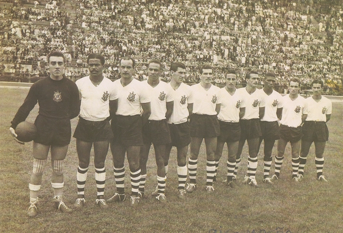 Linda foto do time corintiano, com seus jogadores em pé. O goleiro Cabeção de joelheiras segura a bola (era marrom), em tarde de grande público no Pacaembu. Reparem também nos meiões dos jogadores, diferentes uns dos outros. Da esquerda para a direita: Cabeção, Baltazar (o Cabecinha de Ouro), Touguinha, Lorena, Murilo, Jackson, Carbone, o valente Idário, Julião, Luizinho (o 