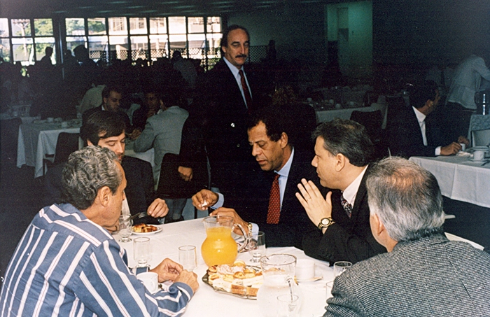 Na imagem, ao lado esquerdo da mesa, está Gylmar dos Santos Neves, enquanto do lado direito aparecem Carlos Alberto Torres, Milton Neves e Mauro Ramos de Oliveira, de costas
