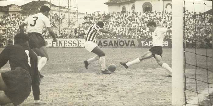 O Corinthians enfrentou o Santos na Vila Belmiro em 07 de dezembro de 1958 e perdeu por 6 a 1. Pelé, o maior algoz do Timão, marcou quatro. Os demais gols santistas foram de Pepe e Pagão. Zague fez o tento de honra para o Alvinegro do Parque São Jorge. Valmir estica toda sua perna direita para tentar roubar a bola do Rei. À esquerda, no chão, o goleiro Gylmar. O camisa 3 é Olavo. Foto: arquivo pessoal de Valmir