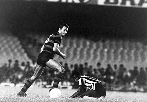 Rondinelli, no Flamengo, em 1976, em partida contra o Atlético Mineiro, no Maracanã. Paulo Isidoro (ex-Galo, Grêmio e Santos) está no chão
