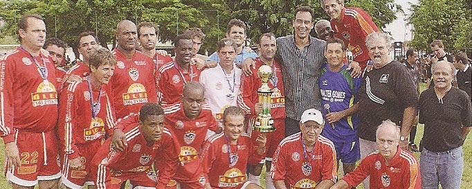 Palmieri, como secretário municipal de esportes foi levar seu abraço aos campeões da Copa Walter Gomes, no Poliesportivo do Comercial Futebol Clube. Ele é o mais alto, de camisa listrada, abraçando dois jogadores. O penúltimo em pé é Tomires, coordenador do evento. Reprodução: Revista Competir, nº 93