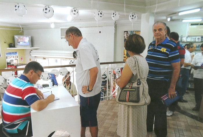 Enquanto Émerson Gáspari autografa o livro de sua autoria para um leitor, Tomires (o terceiro em pé) o aguarda. Foto: Arquivo pessoal