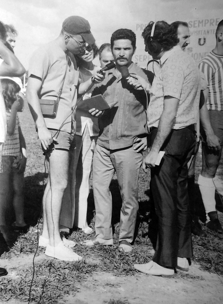 José Nello Marques, repórter da Rádio Clube de Garça (de calção e boné) no ano de 1974 entrevistando Plínio Dias, atleta do Garça FC, que encerrava a carreira e recebia uma placa de agradecimento da diretoria do time garcense. Foto enviada por Tico Cassola