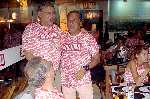 Milton Neves e Galvão Bueno se abraçam no camarote da Brahma, em fevereiro de 2008, no carnaval do Rio de Janeiro. O também jornalista Renato Maurício Prado (sentado) sorri