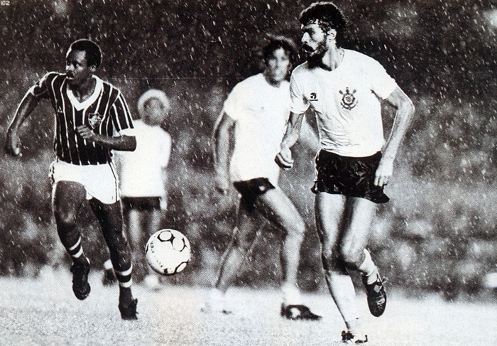 Foto do início dos anos 80 mostra Sócrates carregando a bola, sendo marcado pelo meia Assis. Ao fundo, aparecem Biro-Biro e Paulinho. Foto: Placar
