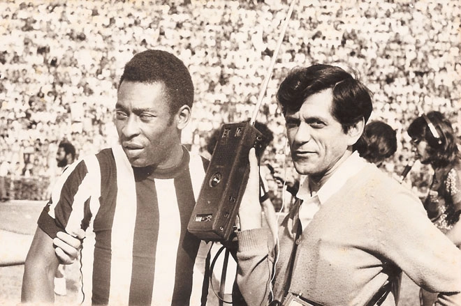 Pelé sendo puxado pelo braço para fazer o aquecimento, enquanto o repórter da Rádio Tupi Marco Antonio olha para a câmera. Atrás do Rei, à esquerda na imagem está Badeco, da Portuguesa. Foto: arquivo pessoal de Benedito Marcantonio