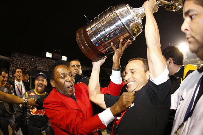 Pelé (de terno vermelho) segura a taça da Copa Libertadores da América junto com o lateral-esquerdo Léo, no dia 22 de junho de 2011. Foto: Site oficial do Santos