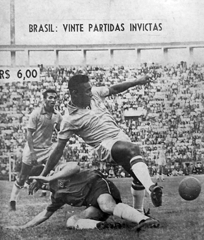 O zagueiro da Seleção Chilena tenta roubar a bola de Pelé, que consegue livrar-se da marcação e fazer o passe. Ao fundo, está Quarentinha, observando a bela jogada. Foto enviada por Walter Roberto Peres