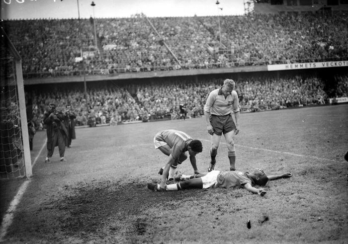 Garrincha ajuda Pelé que está caído no chão devido a câimbras e, enquanto isso, zagueiro sueco observa o atendimento do rival brasileiro. Foto: Reprodução/In My Ear