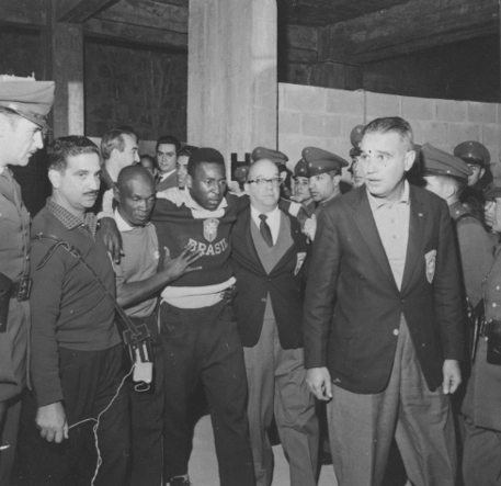 Com o semblante de dor, o Rei sendo carregado por Mário Américo (à esquerda) e Paulo Machado de Carvalho, rumo ao hospital, em 1962. Atrás de Mário Américo, olhando para o lado, João Mendonça Falcão. Foto: Divulgação