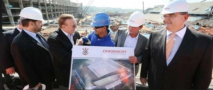 O então presidente da CBF, José Maria Marin, conversou com operários e engenheiros que trabalham no futuro estádio em Itaquera em 15 de junho de 2012.  Na extrema direita, você vê Mário Gobbi e Andrés Sanchez e na esquerda, de barba, o vice-presidente da Federação Paulista de Futebol na época, Reinaldo Carneiro Bastos. Crédito da foto: Portal UOL.