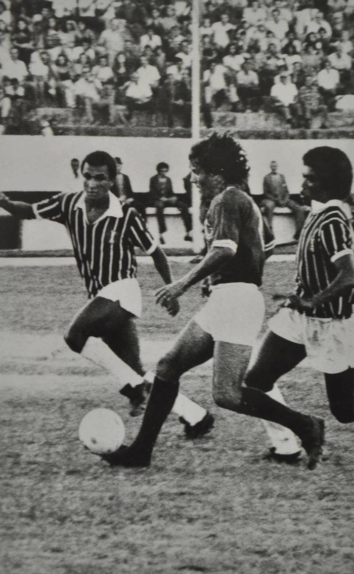 Ednaldo (ao centro) do Guarani carregar a bola enquanto, Ramon (o primeiro) e Luciano Coalhada (o terceiro), ambos do Santa Cruz, observam a arrancada do atacante adversário. Foto: Reprodução do livro 