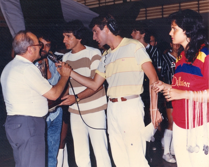 O ex-jogador e técnico Prisco Palumbo, o homem de camisa listrada em branco e verde, e o repórter Antonio Pétrin, com o microfone na mão e o fone de ouvido na cabeça. Foto: Sarkis