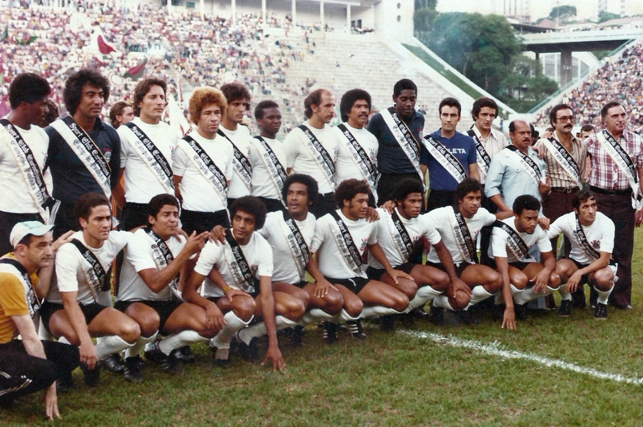 Entrega das faixas do Campeonato Paulista de 1977, antes do jogo Corinthians 2 x 0 Portuguesa (dois gols de Palhinha), válido pelo Campeonato Brasileiro daquele ano. O duelo aconteceu no dia 20 de novembro de 1977. Em pé, da esquerda para a direita, veja Zé Maria, Tobias, Moisés, Russo, Zé Eduardo, Wladimir, Lance, Luciano, Jairo, José Teixeira, Benê Ramos (preparador físico), João Avelino, Renê de Toledo (administrador de futebol) e pessoa não identificada. Agachados, também da esquerda para a direita, estão Rocco (Massagista), Palhinha, Vaguinho, Basílio, Geraldão, Romeu, Cláudio Mineiro, Daércio, Adãozinho e Ademir Gonçalves. Foto: Arquivo pessoal da repórter Germana Garilli