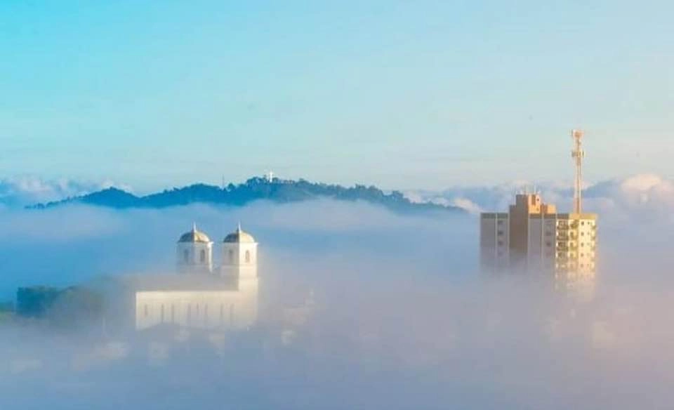 Em janeiro de 2020, nevoeiro cobrindo parcialmente a cidade de Muzambinho. Na imagem, aparecem a Paróquia São José e o edifício Carmen Fernandes Neves. Foto: Reprodução