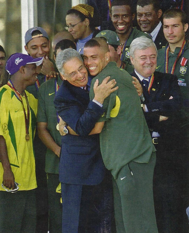 O então presidente Fernando Henrique Cardoso abraça Ronaldo após a conquista da Copa de 2002. À esquerda, Edílson e atrás dele, com o boné ao contrário, Gilberto Silva. À direita, Ricardo Teixeira. Atrás, sorrindo, Roque Júnior, pessoa não identificada e Luizão. Foto: Roberto Stucker Filho/O Globo, publicada na Revista Veja em 16 de julho de 2014