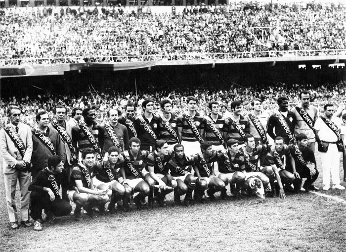 O elenco do Atlético Paranaense, posando com as faixas de campeão estadual de 1970. Da esquerda para a direita, em pé: Alfredo Ramos, pessoa não identificada, Claudio Passerino Moura (ex-presidente, já falecido), J. Hawilla (atrás), Djalma Santos, dirigente não identificado, Rubens (goleiro), Vanderlei, Zico, Alfredo e Júlio. Agachados: Moraes Chiclete, Gildo, Zé Leite, Sicupira, Nelsinho, Ferrinho, Toninho e Nilson Bocão