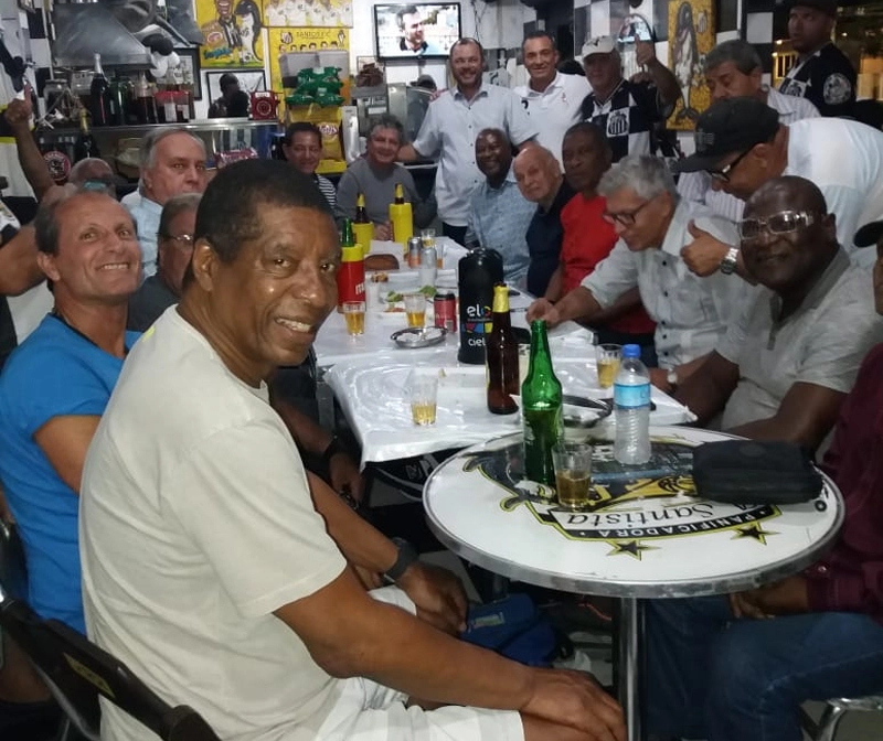 Amigos reunidos na Padaria do Carlinhos em 23 de outubro de 2018, dia em que Pelé comemorou 78 anos. Sentados, no sentido horário, veja Everaldo (à frente), Mauro Patrício, Nenê Belarmino, Aluísio Guerreiro, Carlito Macedo, Manuel Maria, Edu, Pepe, Adilson e Clodoaldo. Em pé, Joãozinho Rosa está ao meio, tendo Carlinhos (da Padaria do Carlinhos) ao seu lado. 