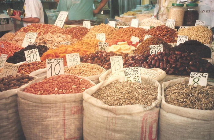 O colorido maravilhoso das frutas em um mercado com venda à granel. Tâmaras, castanhas, damascos e ameixas, entre outras