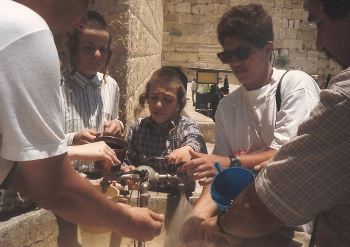 Lenice Neves (da direita para a esquerda, a segunda), entra na fila para pegar um pouco de água e saciar a sede e envolta dela judeus de todas as idades, crianças, adolescentes e adultos