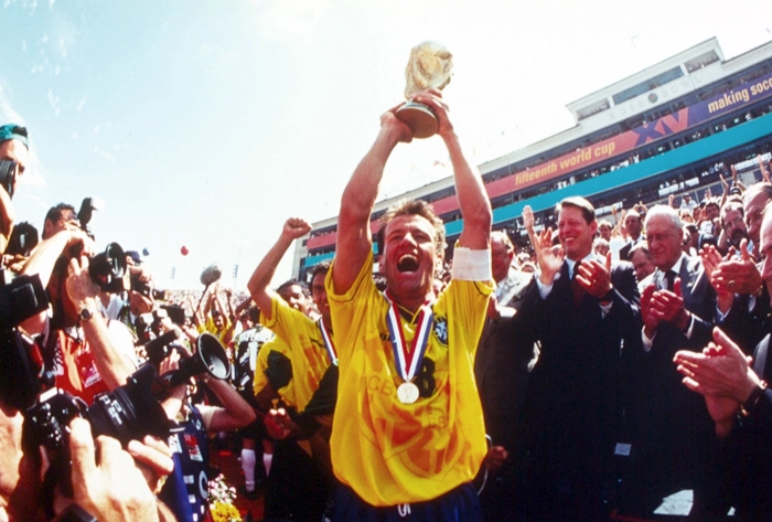 Dunga levanta a quarta taça mundial conquistada pela Seleção Brasileira, enquanto João Havelange o observa, à esquerda. Atrás do capitão, aparecem, na ordem, Branco, Viola e Taffarel. Foto: Reprodução/In My Ear