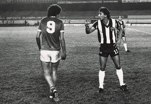 Em 1982, emprestado pelo Corinthians para a Caldense, Casagrande não diminuiu o seu ímpeto pela vitória. Na foto, o irreverente atacante encara Éder Aleixo, na época, atacante do Atletico Mineiro. Atrás dos dois jogadores, veja o atacante Palhinha, observando a discussão. Crédito foto: Revista Placar/Auremas Castro