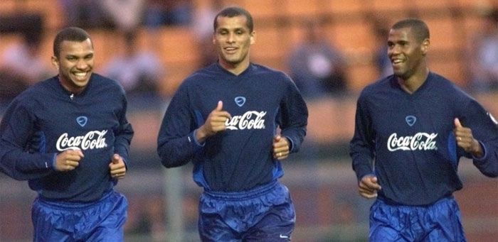  O ex-atacante Amoroso corre ao lado de Rivaldo e Aldair em treino da seleção brasileira, em 2000. Crédito da foto: Eduardo Knapp/Folhapress, via Portal UOL. 