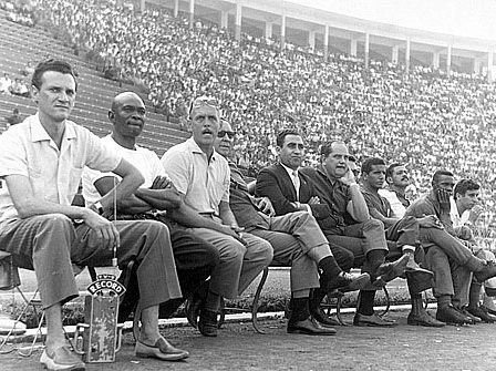 A foto é do saudoso Sarkis e é maravilhosa. Aymoré, com os óculos na testa, está ligadíssimo no clássico entre Corinthians e Portuguesa, em 1964, no Pacaembu. O primeiro repórter à esquerda é o também saudoso Tom Barbosa, ex-rádios Record e Jovem Pan. Mário Américo é o segundo, igualmente falecido. O antepenúltimo, da esquerda para a direita, é o bigodudo Ipojucan, então auxiliar técnico de Aymoré. Ipojucan também já morreu. O quarto é o zagueiro de área Wilson Silva.