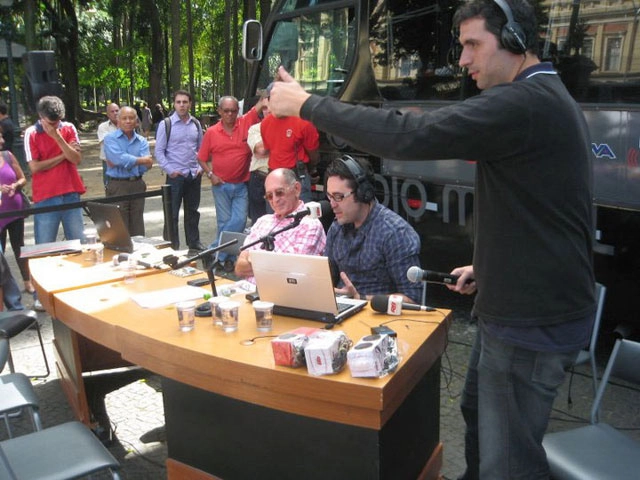 José Silvério junto com Sérgio Patrick, estão sentados na bancada e Estevan Ciccone à direita fazendo sinal de positivo