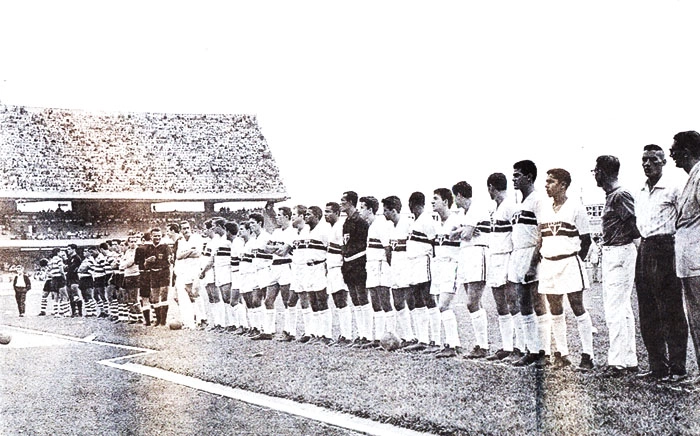 Times de São Paulo e Sporting-POR perfilados no dia 2 de outubro de 1960, na inauguração do Estádio do Morumbi. Na foto, da direita para esquerda, o segundo é o treinador José Teixeira, o oitavo é Roberto Dias, Canhoteiro é o 13º, Gildésio é o 16º, Peixinho o 18º, o 20º é Vítor, o goleador Gino é 22º, seguido pelo goleiro Poy e o árbitro Olten Ayres de Abreu. Ademar, Riberto e Gonçalo também participaram deste amistoso internacional. Foto: Reprodução/José Castro/Folhapress