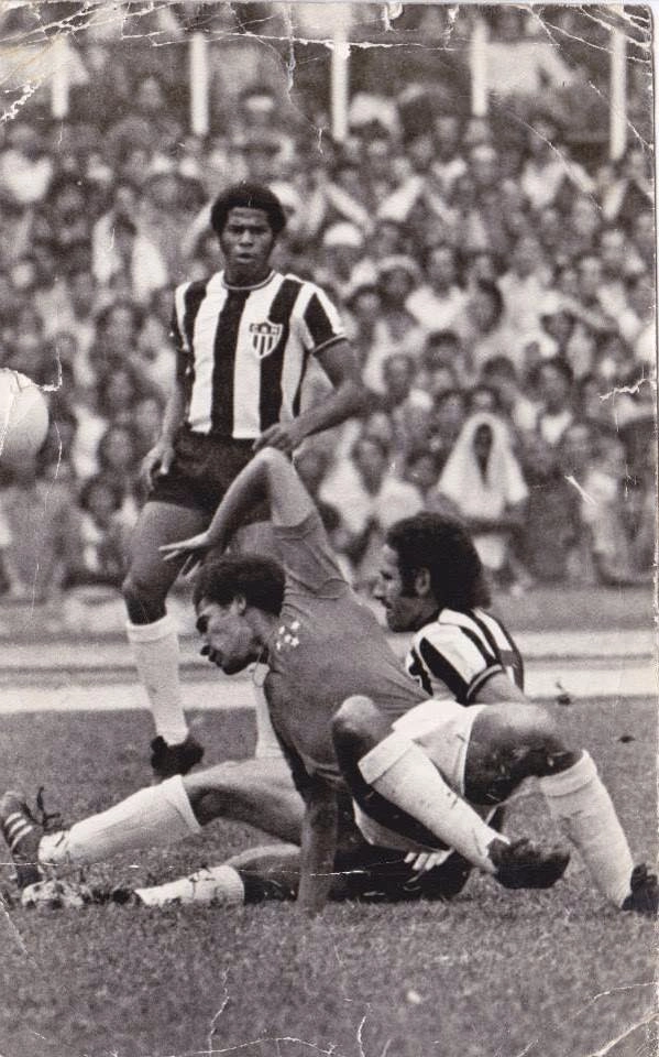 Normandes e Roberto Batata estão no chão na disputa de bola, sendo observados por Claudio Mineiro
