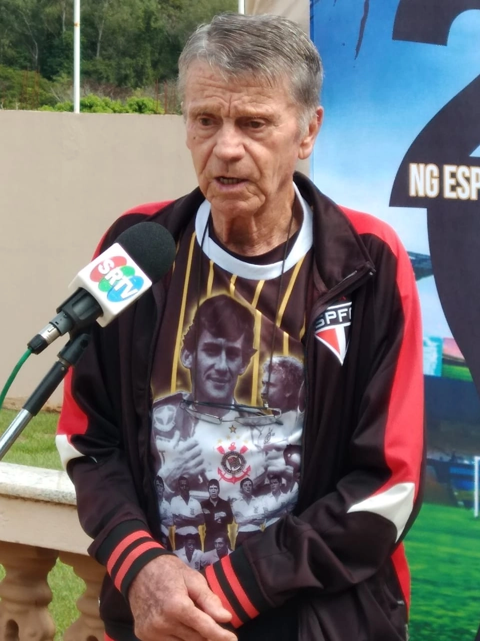 Sendo entrevistado pela SRTV. Reparem que ele veste uma camiseta de Ayrton Senna, alusiva ao Corinthians e um agasalho do São Paulo, demonstrando o coração dividido do ex-jogador pelos clubes que defendeu. Foto: Divulgação