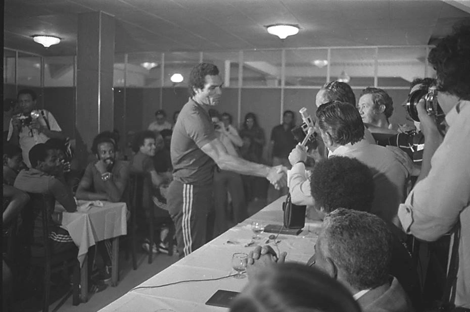 No dia 8 de março de 1977 jogadores da seleção brasileira receberam do então Ministro do Trabalho, Arnaldo Prieto, carteiras de trabalho como jogadores profissionais. O ex-goleiro Manga recebe a sua. Sentados observando aparecem Jairo, Amaral e Beto Fuscão, na primeira mesa, e Joãozinho, na segunda.