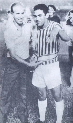 Veja Garrincha, quando jogava pelo Olaria, em 1972, recebendo de Zagallo a faixa de campeão do mundo de 70, em reconhecimento às suas notáveis participações nas Copas de 1958 e 1962. A foto é do livro 