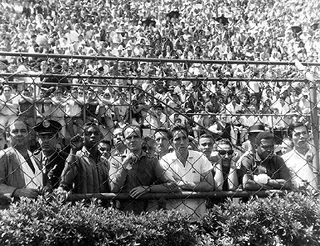 Em 1965, o Pacaembu estava lotado para um jogo do fantástico Santos. E será que os jogadores de hoje poderiam ver a uma partida preliminar lado a lado com os torcedores? Bons tempos. A violência quase não existia, muito menos guerra de organizadas. Aqui, da esquerda para a direita, os craques santistas Lima, Modesto (atrás de Pepe), Pepe, Toninho Guerreiro (camisa branca) e Coutinho observam ao jogo preliminar. Um torcedor está entre os goleadores Toninho Guerreiro e Coutinho. Ao lado do versátil Lima, um guarda civil. Imagina se hoje seria possível aos craques dar uma espiadinha em alguma partida de futebol ao lado da galera? A foto, de rara sensibilidade, tem a assinatura do saudoso fotógrafo Sarkis. Conheça sua história clicando 