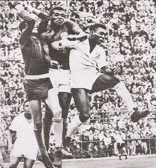 Disputando a bola estão Pelé, Ditão e o goleiro Félix. Ao fundo, Coutinho aguarda o desfecho do lance.