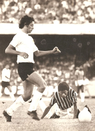 No Morumbi, Luís Carlos avança com a bola toda branca à sua frente. O são-paulino Zé Carlos, caído, observa