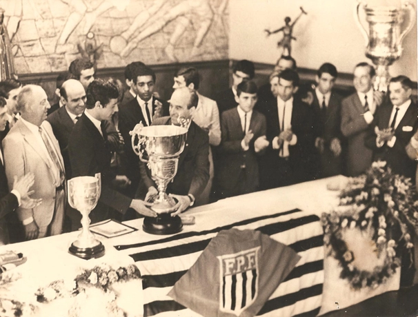 Luís Carlos Galter e João Mendonça Falcão estão com as mãos na taça. Atrás de Luís Carlos está o sorridente Mário Travaglini e ao fundo, Paulo Davoli. Basílio está entre Luís Carlos e Mendonça Falcão e no canto direito, de bigode, está João Atala, ex-funcionário da Federação Paulista de Futebol