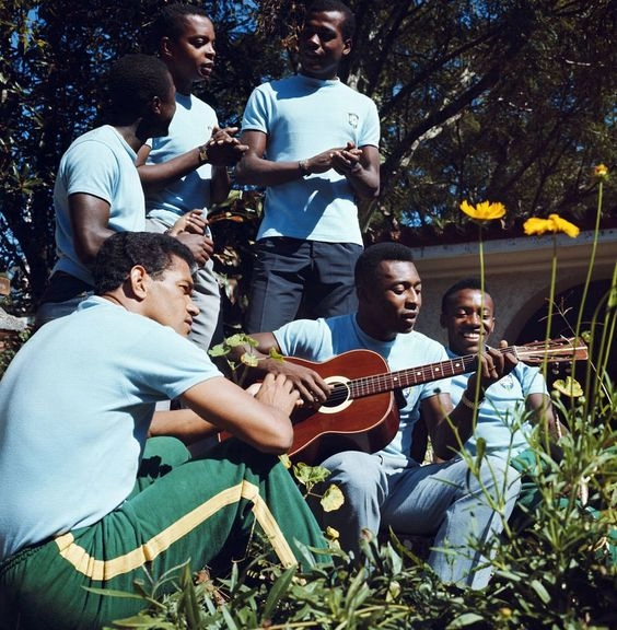 Preparativos para a Copa da Inglaterra, em 1966. Em pé e batucando com as mãos estão Edu, Lima e Denilson. Sentados na grama vemos Garrincha, com o olhar perdido ao lado do cantor e violinista Pelé. O último, de sorriso largo é Ivair. Foto: Reprodução